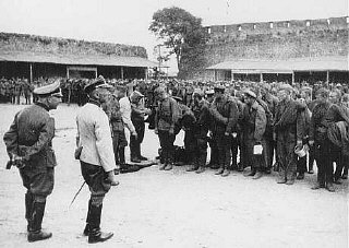 Soviet prisoners of war interrogated by German soldiers upon arrival at a prison camp.
