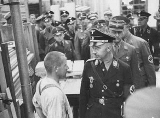 Heinrich Himmler, head of the SS, speaks to an inmate of the Dachau concentration camp during an official inspection.