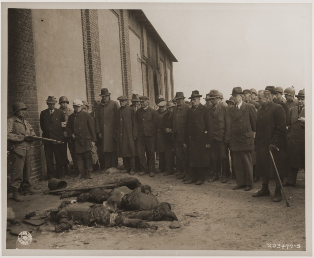 An American soldier stands guard as mayors and citizens of local towns view the corpses of inmates of the Rottleberode subcamp, who ... [LCID: 76687]