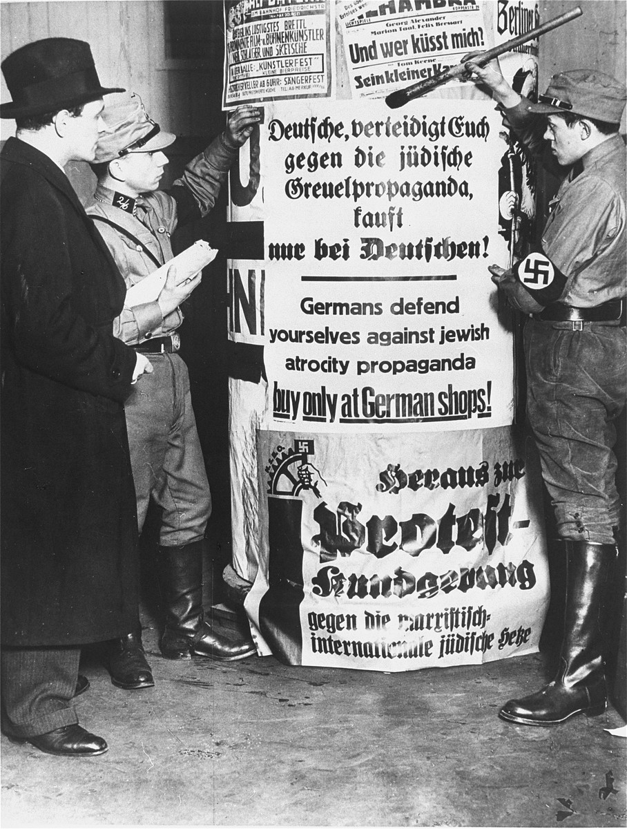 SA men post signs demanding that Germans boycott Jewish-owned businesses. [LCID: 4049]