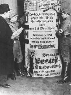 SA men post signs demanding that Germans boycott Jewish-owned businesses.