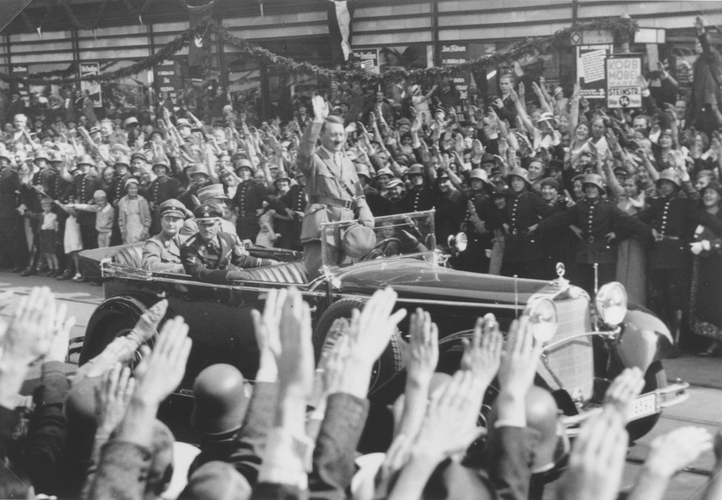 Adolf Hitler salutes a crowd lining the streets of Hamburg