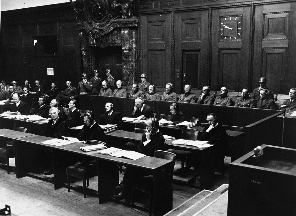 The defendants in the dock (at rear, with headphones) and their lawyers (front) follow the proceedings of the Hostage Case. [LCID: 16806]
