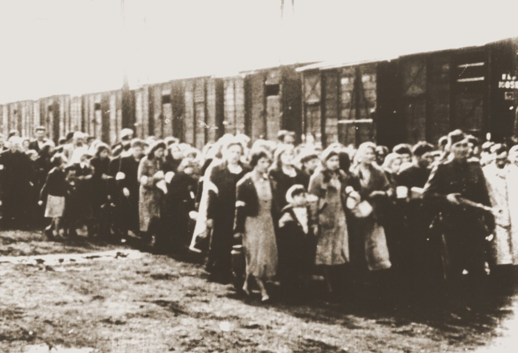 Jews being deported from the Warsaw ghetto march to the freight trains. [LCID: 05554]
