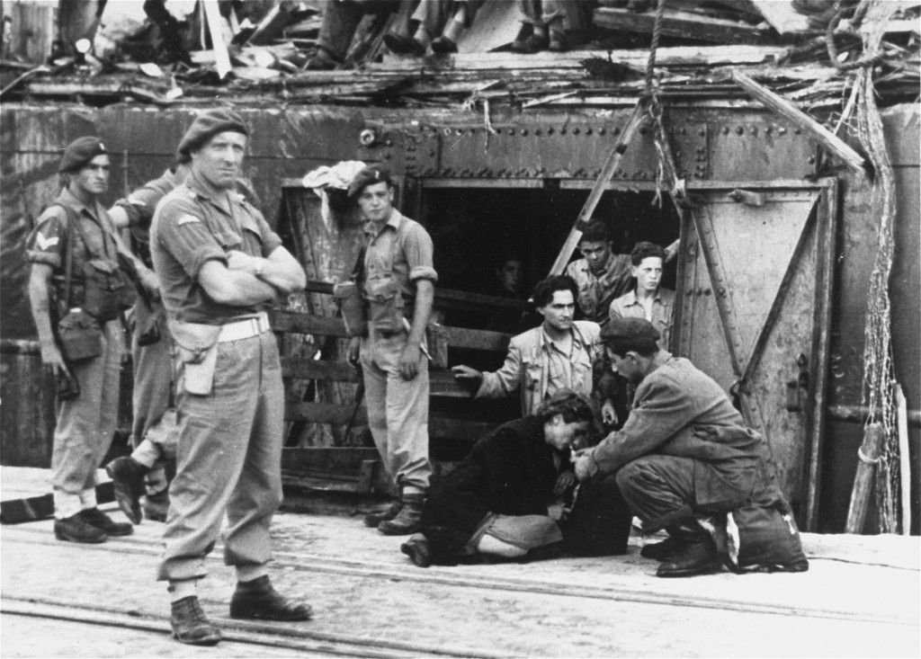 An exhausted Jewish woman from the "Exodus 1947" refugee ship is given a drink as British soldiers stand nearby. [LCID: 69776]