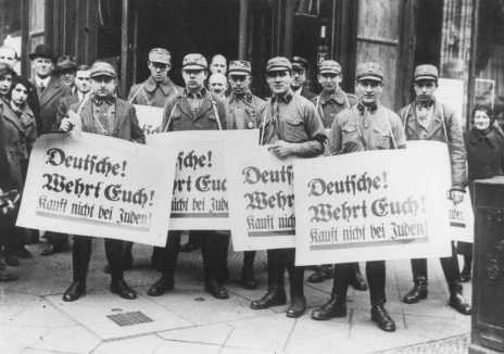 During the anti-Jewish boycott, SA men carry banners which read "Germans! [LCID: 12359]