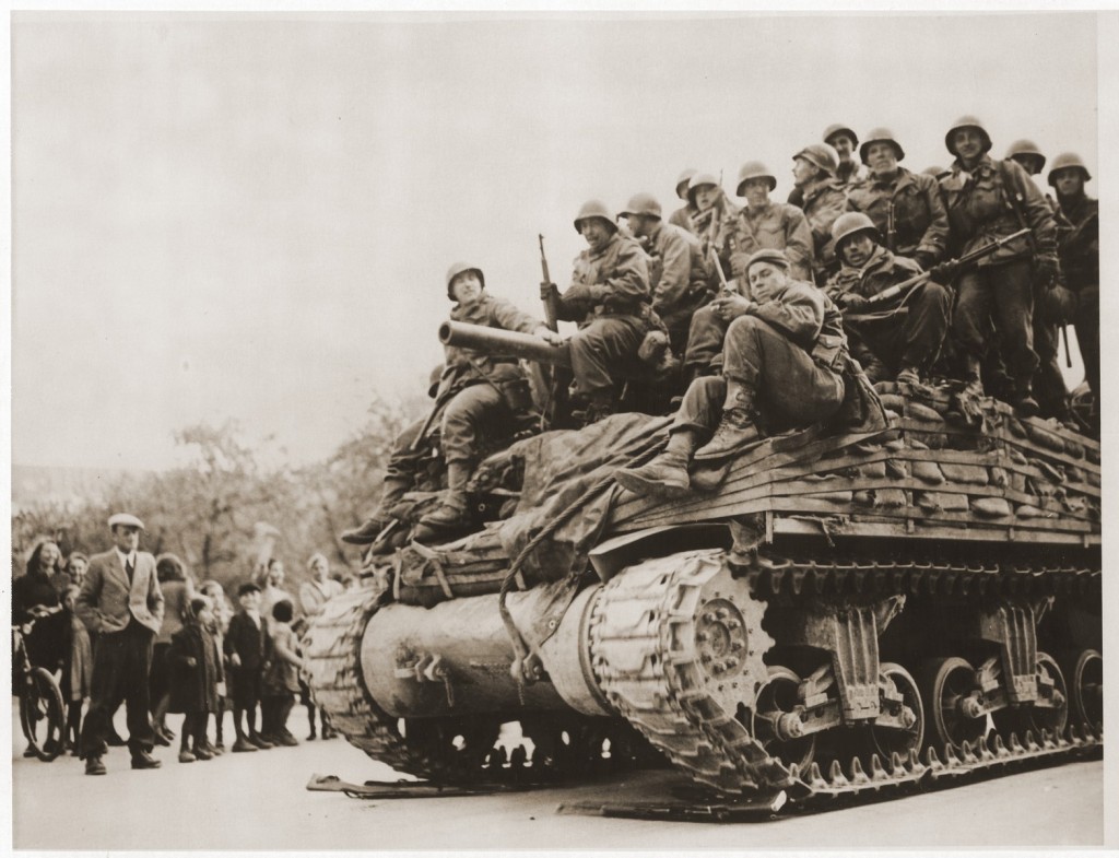A tank with 7th US Army infantrymen of the 103rd Infantry Division rolls through Innsbruck, Austria, 1945