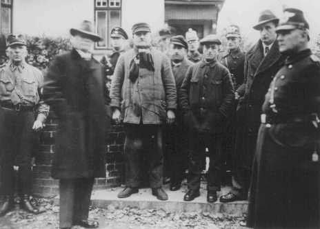 Jews arrested during Kristallnacht stand under guard before being deported to the Sachsenhausen concentration camp. [LCID: 4373]