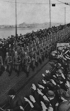 <p>During the remilitarization of the Rhineland, German civilians salute German forces crossing the Rhine River in open violation of the <a href="/narrative/116">Treaty of Versailles</a>. Mainz, Germany, March 7, 1936.</p>