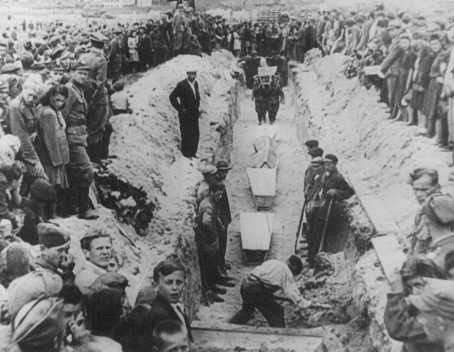 Mourners crowd around a narrow trench as coffins of pogrom victims are placed in a common grave, following mass burial service.