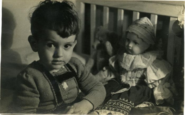 Villiam Krausz (Benjamin Kedar) sits with a doll and a teddy bear shortly before the family went into hiding.
