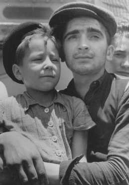 Eight-year-old Yisrael Meir (Lulek) Lau is held by a fellow  Buchenwald survivor, Elazar Schiff, as they arrive in Palestine aboard the RMS "Mataroa."