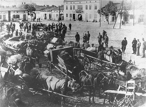 German troops stand in the town sqaure of Przyrow where dozens of horse-drawn wagons are gathered presumably during a resettlement action [LCID: 03943]