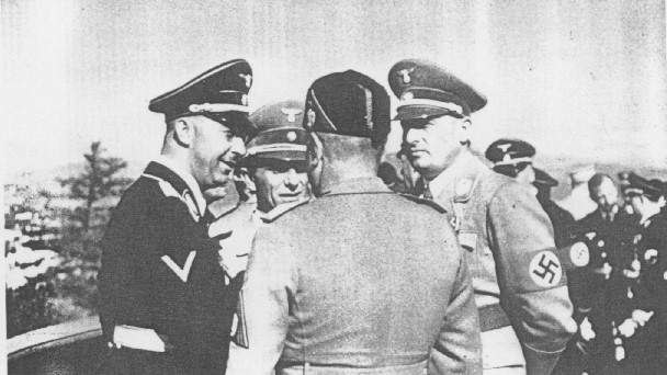 During a visit to Germany, Italian dictator Benito Mussolini (back to camera)  speaks with (left to right): SS chief Heinrich Himmler; Nazi propaganda minister Joseph Goebbels; and Nazi governor of Poland Hans Frank.