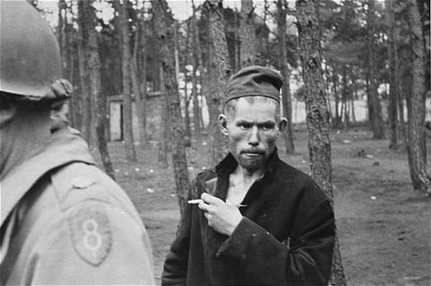 A survivor in Wöbbelin. The soldier in the foreground of the photograph wears the insignia of the 8th Infantry Division.