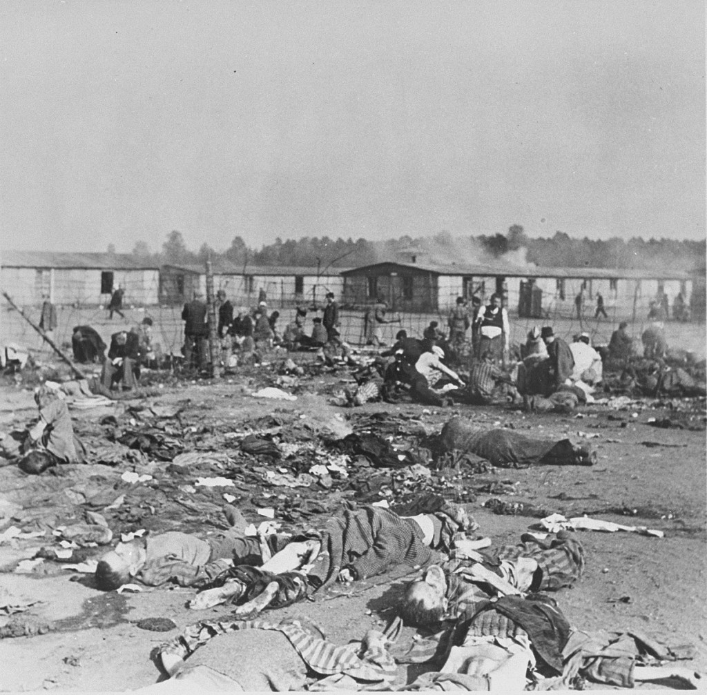 Soon after liberation, camp survivors eat near scattered corpses. [LCID: 74108]