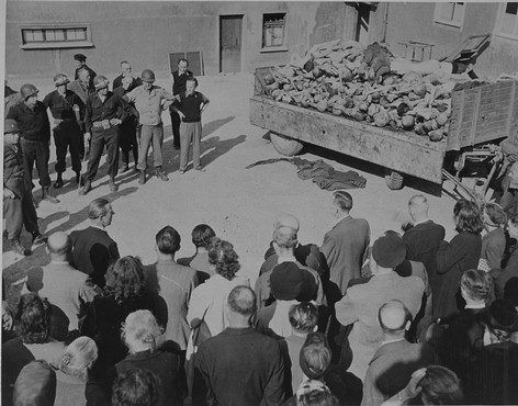 German civilians under US military escort are forced to view a wagon piled with corpses in the newly liberated Buchenwald concentration camp.