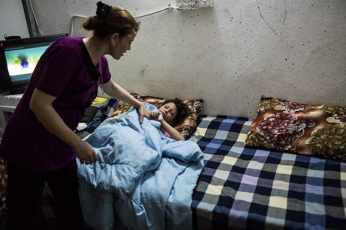 A mother checks on her sick daughter inside the container where they live in an internally displaced persons (IDP) camp near Erbil, ... [LCID: ref03]