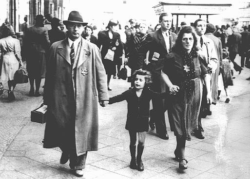 Members of a Jewish family walking along a Berlin street wear the compulsory Star of David.