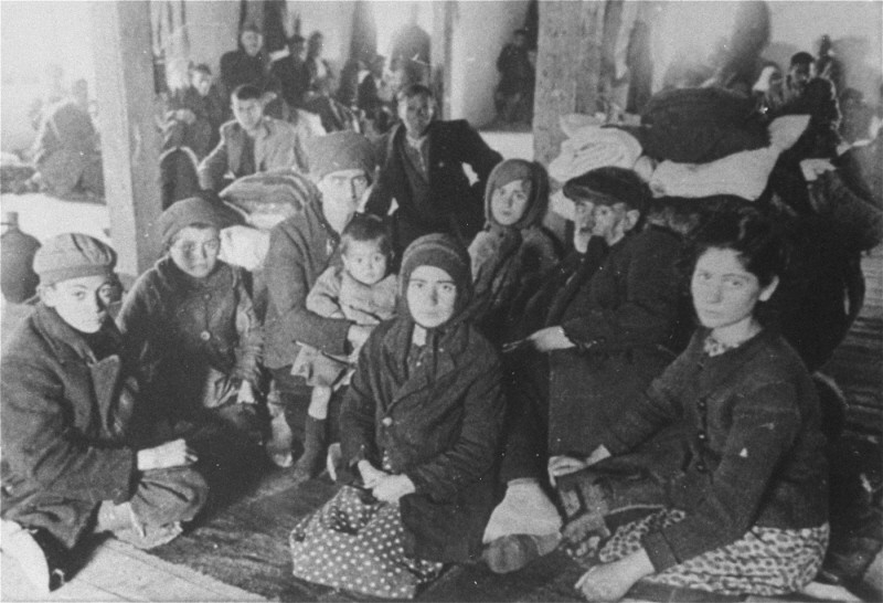 Jews from Macedonia who were rounded up and assembled in the Tobacco Monopoly transit camp before deportation to the Treblinka killing center. Skopje, Yugoslavia, March 1943.
The Jews of Bulgarian-occupied Thrace and Macedonia were deported in March 1943. On March 11, 1943, over 7,000 Macedonian Jews from Skopje, Bitola, and Stip were rounded up and assembled at the Tobacco Monopoly in Skopje, whose several buildings had been hastily converted into a transit camp. The Macedonian Jews were kept there between eleven and eighteen days, before being deported by train in three transports between March 22 and 29, to Treblinka.