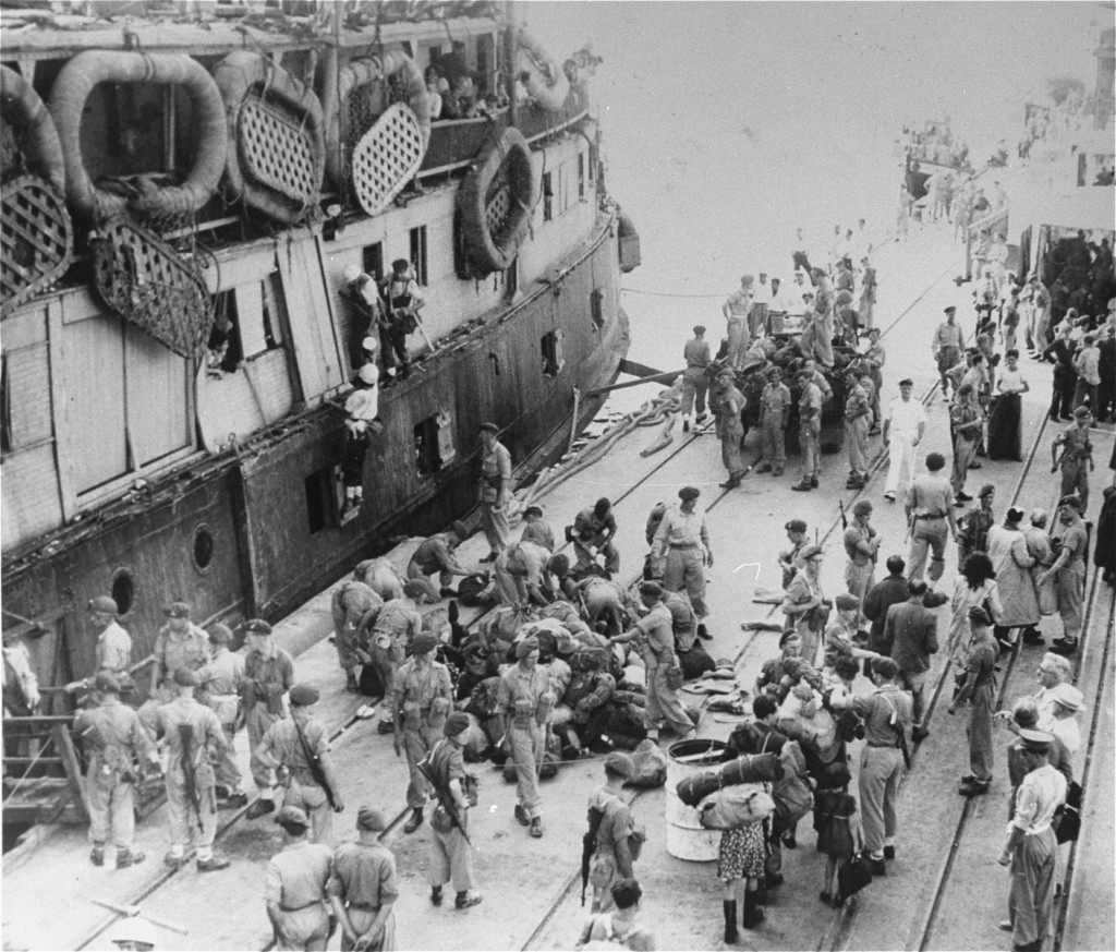 As UN official Emil Sandstroem (bottom right, white hat) looks on, British soldiers remove Jewish refugees from the ship "Exodus ... [LCID: 69913]