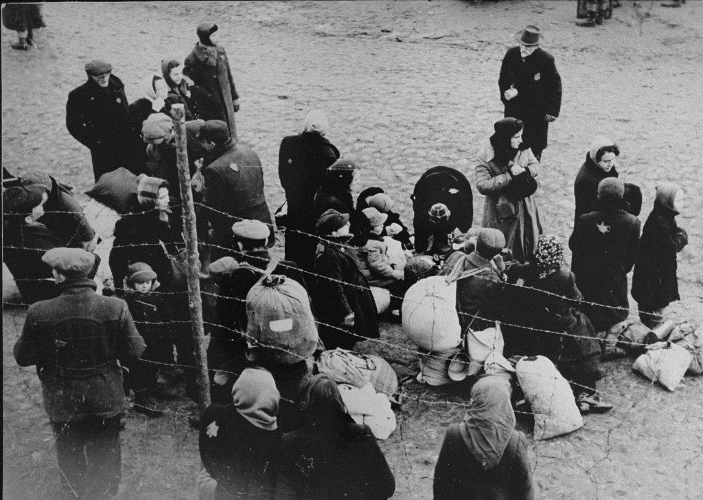 Jewish families with bundles of belongings during deportation from the Kovno ghetto to Riga in neighboring Latvia. [LCID: 81090]