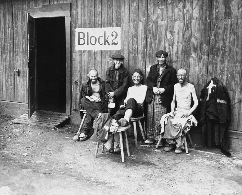 Five Jewish survivors pose for a US Signal Corps photographer in front of Block 2 in the Hanover-Ahlem camp, a subcamp of Neuengamme.