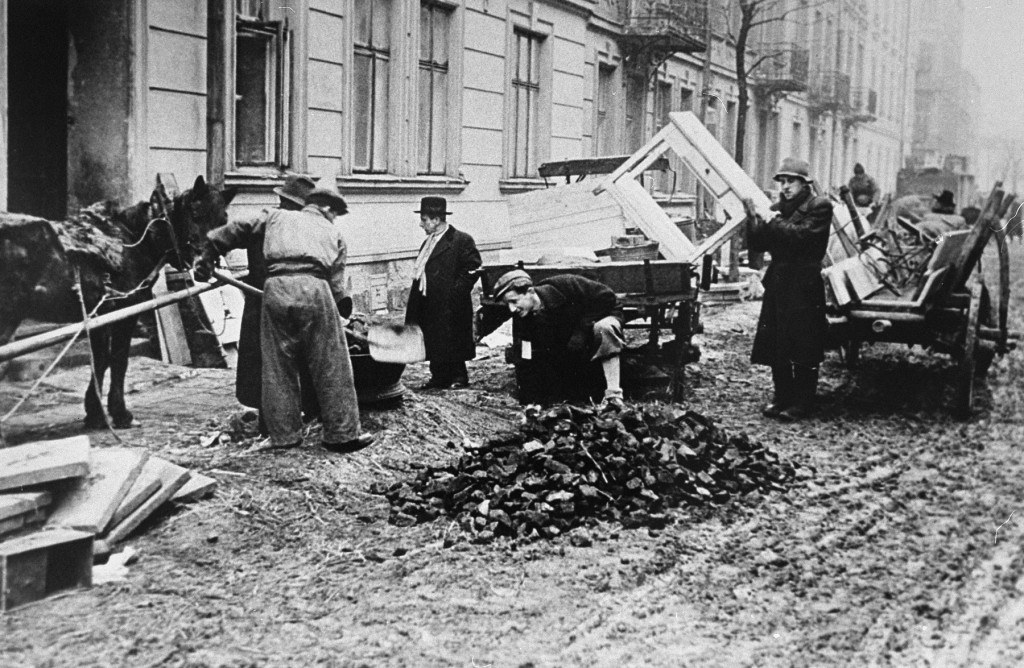 Jews in the Krakow ghetto unload furniture, to be used as kindling, next to a pile of coal. [LCID: 49023]