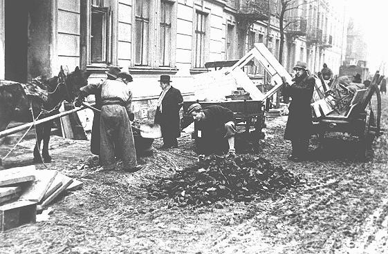 Jews in the Krakow ghetto unload furniture, to be used as kindling, next to a pile of coal. [LCID: 49023]