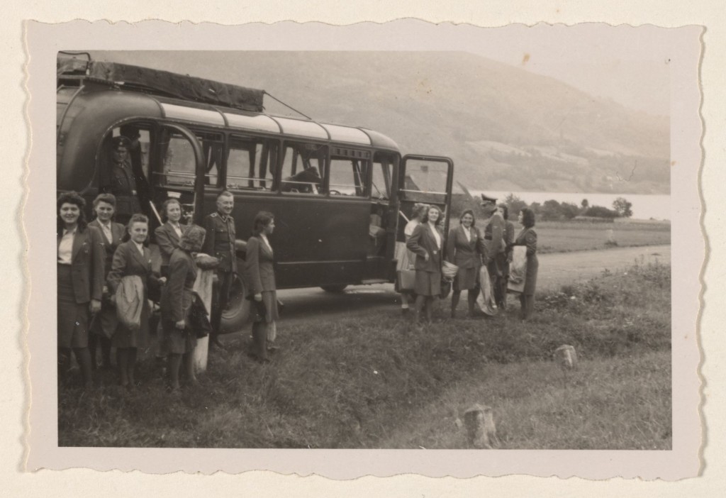 SS female auxiliaries getting off the bus on a day trip in July 1944; this image contrasts starkly with the arrival of a transport ...