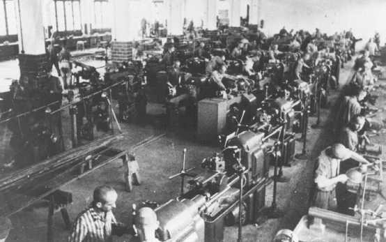 Prisoners at forced labor under SS guard in an armaments factory.