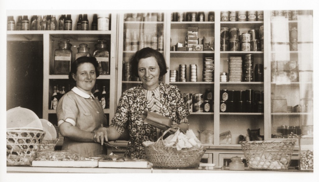 Two German Jewish refugee women stand behind the counter of the Elite Provision Store (delicatessen) in Shanghai. [LCID: 38027]