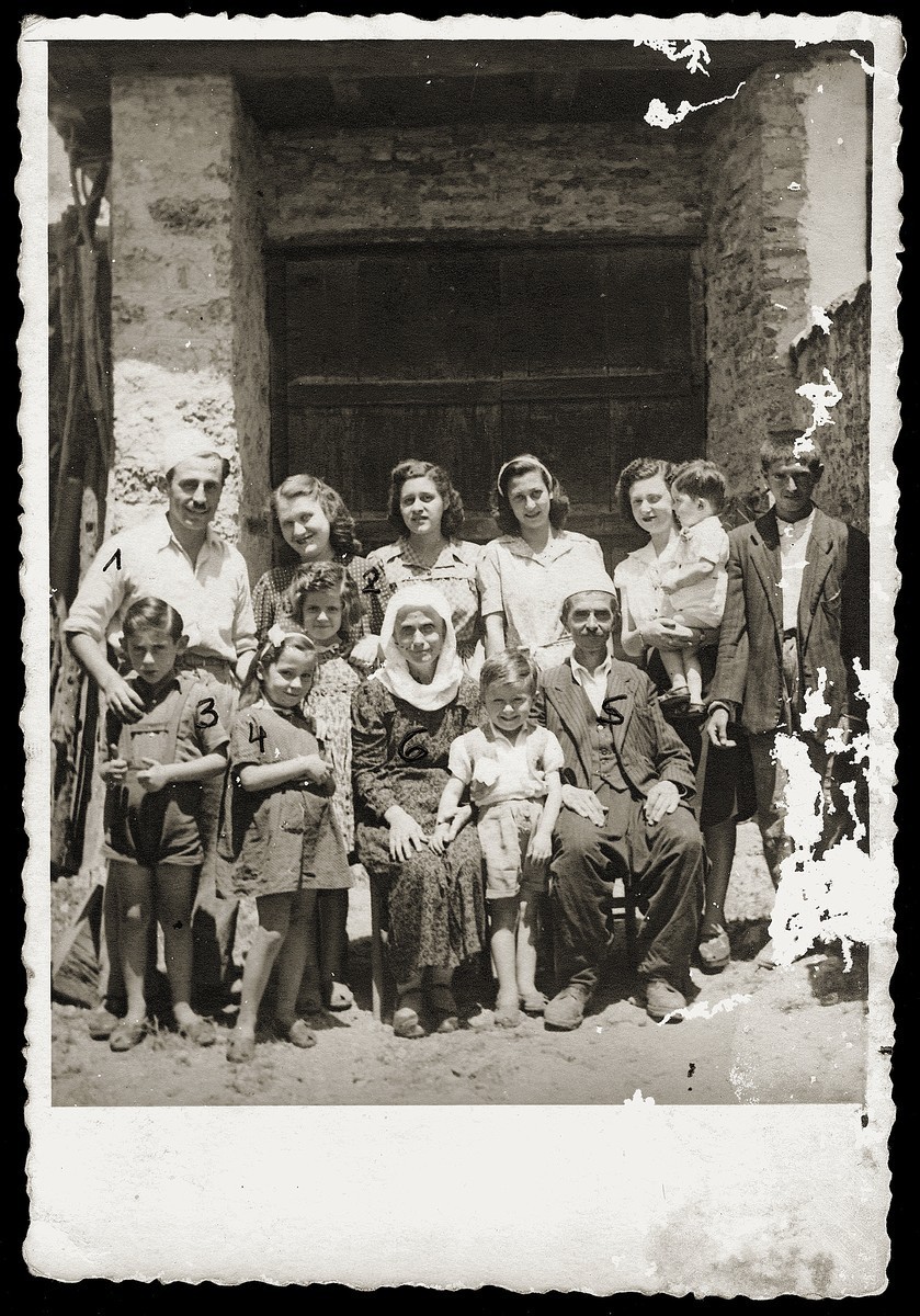 <p><span style="font-weight: 400;">Pictured in the front row and identified with numbers are Gavra Mandil (3), Irena Mandil (4), Fatima Veseli (6), and Vesel Veseli (5). Standing behind them are Mosa (1) and Gabriela (2) Mandil. Kruje, Albania, circa July 1944.</span></p>
<p><span style="font-weight: 400;">The Mandil family traveled from Tirana to the Veselis’ home in Kruje under the cover of night. Mosa and Gabriela had to stay hidden in a room above the Veselis’ barn. Gavra and Irena were able to live disguised as Muslim Albanians and could move about town and play with the other children. The Veselis also sheltered another Jewish family who had worked in the clothing shop owned by Refik Veseli’s brother. Their neighbors became aware that the Veselis were hiding Jewish refugees but did not report them to German authorities. The Veselis </span><a href="https://encyclopedia.ushmm.org/content/en/article/rescue"><span style="font-weight: 400;">sheltered and provided</span></a><span style="font-weight: 400;"> for the families until the region was liberated from German control in late 1944.</span></p>