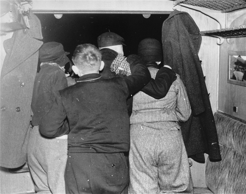Four children look out of a train window with their backs to the camera.