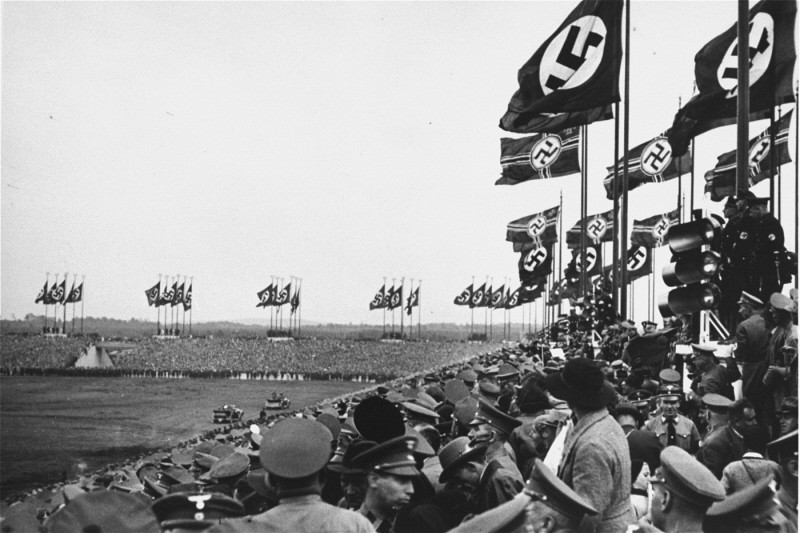 Spectators in the stands of the Zeppelinfeld look on as Adolf Hitler's car moves towards the speakers' platform at the opening of Reichsparteitag (Reich Party Day) ceremonies in Nuremberg. The Zeppelinfeld was part of the Nazi Party rally grounds. Nuremberg, Germany, September 1935.