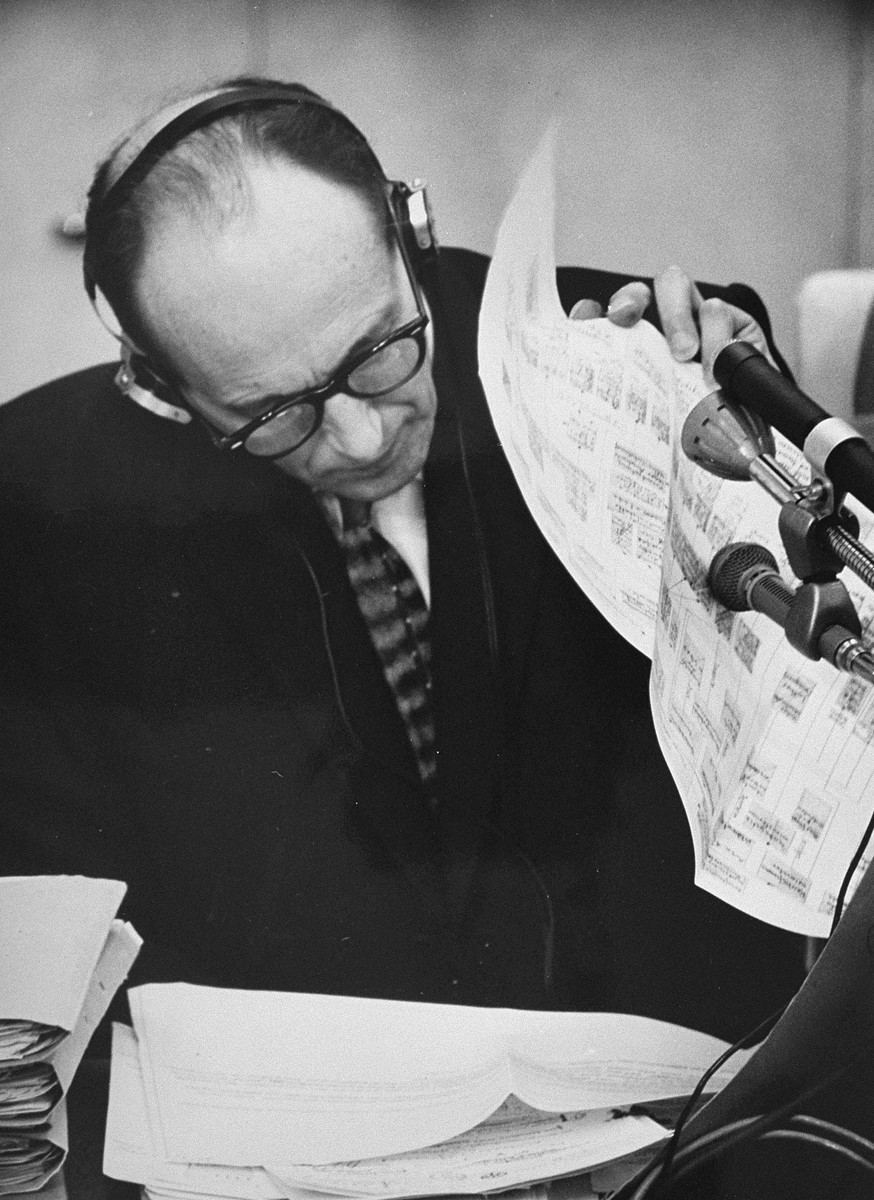 During his trial, defendant Adolf Eichmann reads a chart outlining the administrative hierarchy of the German Third Reich.
