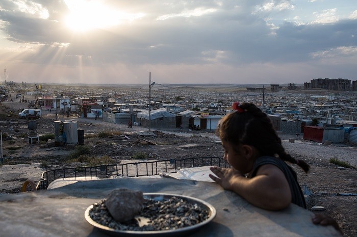 A Syrian girl looks over the Domiz refugee camp outside Duhok, Iraqi Kurdistan. [LCID: ref07]