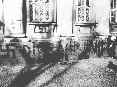 <p>A German youth defaces a Berlin synagogue. The grafitti reads: "Vengeance is nearing." Berlin, Germany, November 1938.</p>