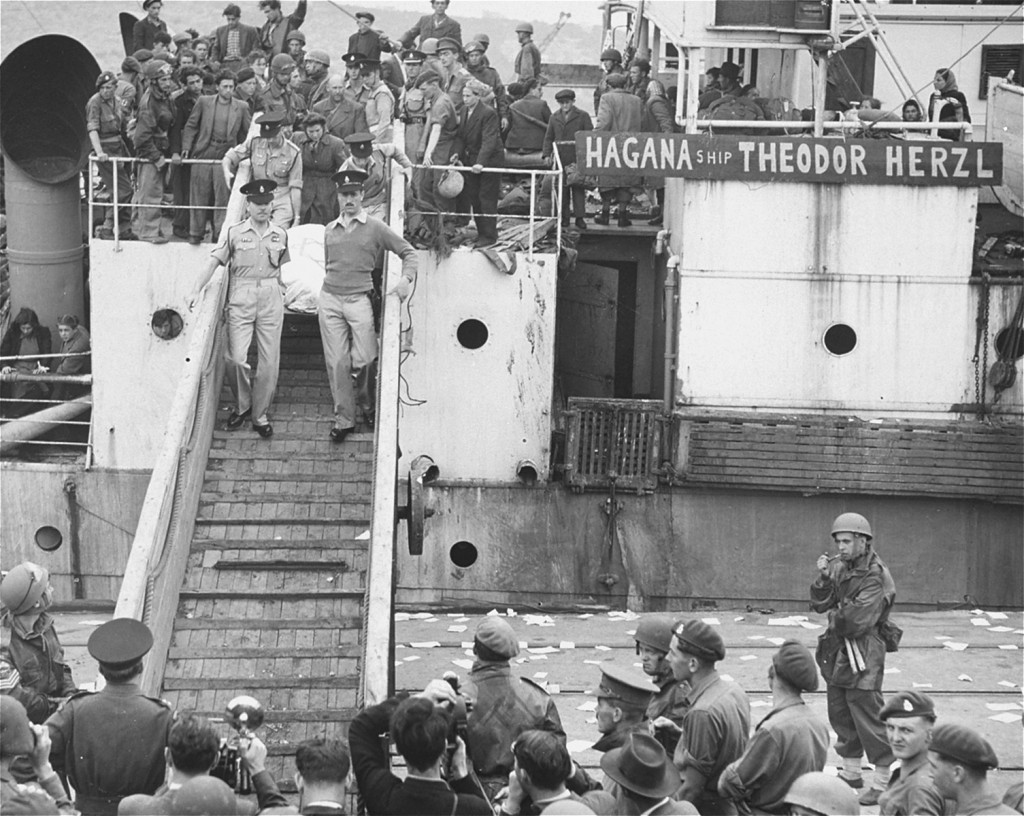 British soldiers remove the body of a refugee (draped in a Jewish flag), killed aboard the refugee ship "Theodor Herzl" during its ... [LCID: 69185]