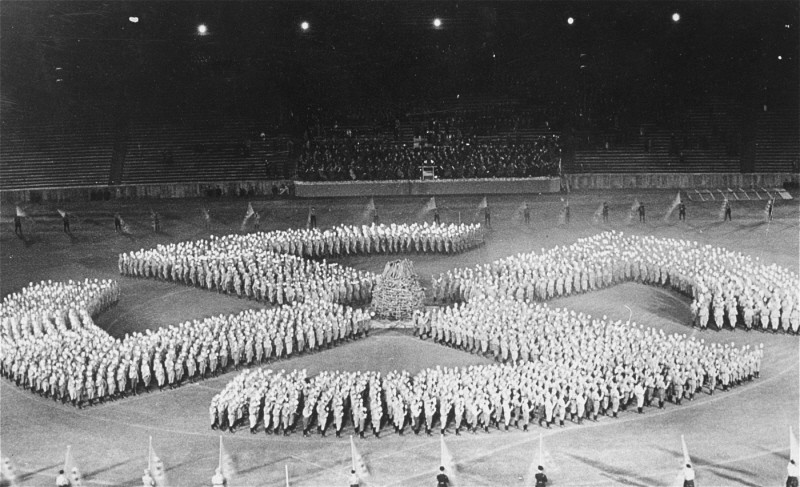 At a rally, members of the Hitler Youth parade in the formation of a swastika to honor the Unknown Soldier. Germany, August 27, 1933.