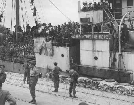 Refugees on board Aliyah Bet ("illegal" immigration) ship "Theodor Herzl" carry bodies (in white shrouds) of two passengers slain when the ship tried to run a British blockade.
