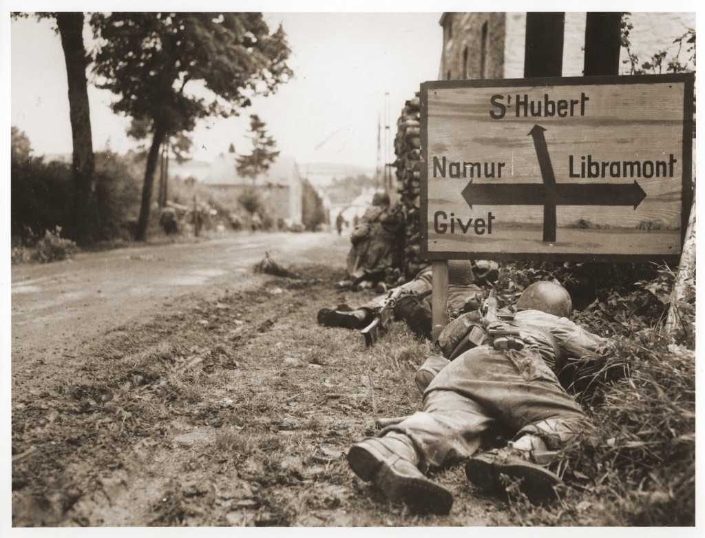 American soldiers of the 8th Infantry Regiment seek cover behind hedges and signs to return fire to German forces holding the town ...