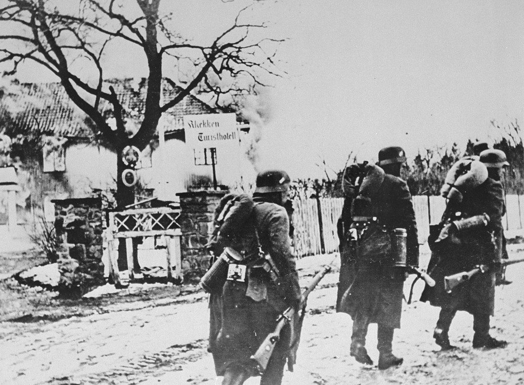 <p>German troops walk past a burning hotel during the invasion of Norway. Norway, April-June 1940.</p>