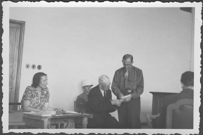 US prosecutor Robert Kempner shows a document to German Field Marshal Erich von Manstein at the International Military Tribunal commission hearings investigating indicted Nazi organizations. Also pictured is the interpreter, a Mrs. Lowenstein. July 1946.