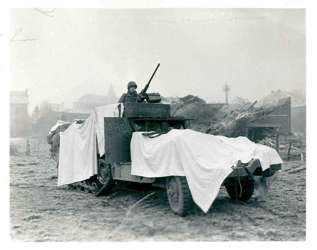 A member of the US Army 10th Armored Division riding a snow camouflaged truck, 1944