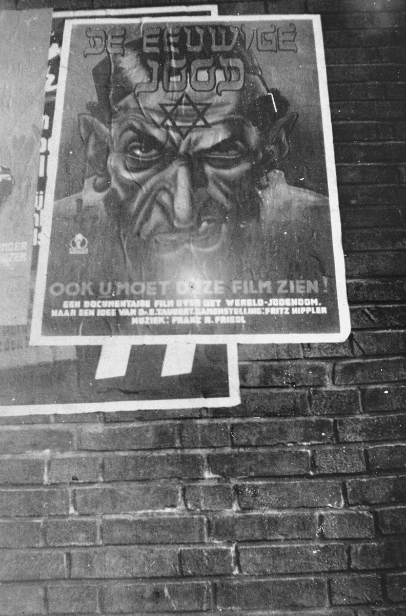 A poster advertising the antisemitic propaganda film "Der ewige Jude" (The Eternal Jew) hangs on the side of a Dutch building.
