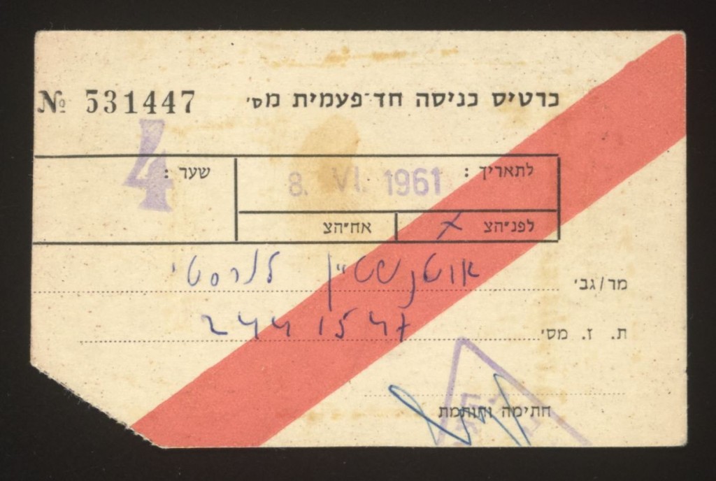 Paper entry pass with a bright orange diagonal line running from bottom left to top right. The bottom left corner has been cut off. Pass is number 5-3-1-4-4-7 with black printed type, handwritten blue ink, and remnants of a light purple stamp.
