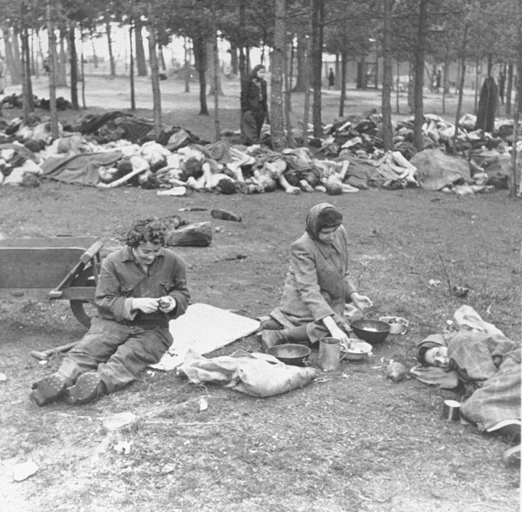 Soon after liberation, women camp survivors prepare food near piles of dead bodies. [LCID: 32080]