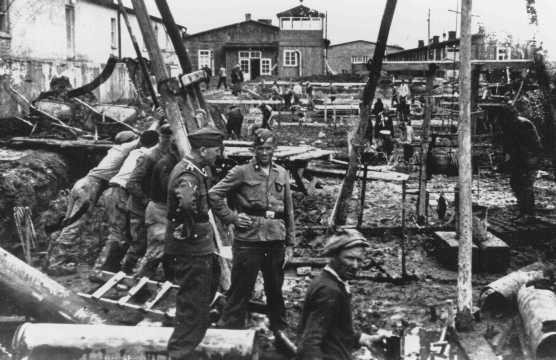 SS men supervise laborers at construction work. Neuengamme concentration camp, Germany, winter 1943.