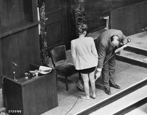 Concentration camp survivor Jadwiga Dzido shows her scarred leg to the Nuremberg court, while an expert medical witness explains the nature of the procedures inflicted on her in the Ravensbrück concentration camp on November 22, 1942.